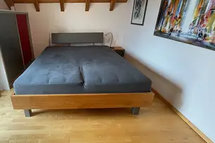 Kirschbaumbett mit grauem Leder auf dem Betthaupt, der Schubladenblende und den Füßen