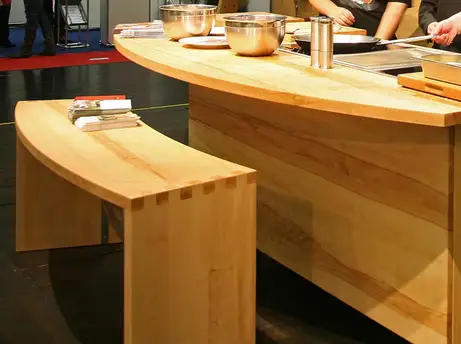 Buchenmassivholzküche mit segmentbogenförmigen Mittelzentrum und dazu passender Sitzbank