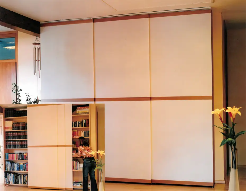 Die Bücherwand aus Ahorn wurde mit Flächenvorhängen versteckt